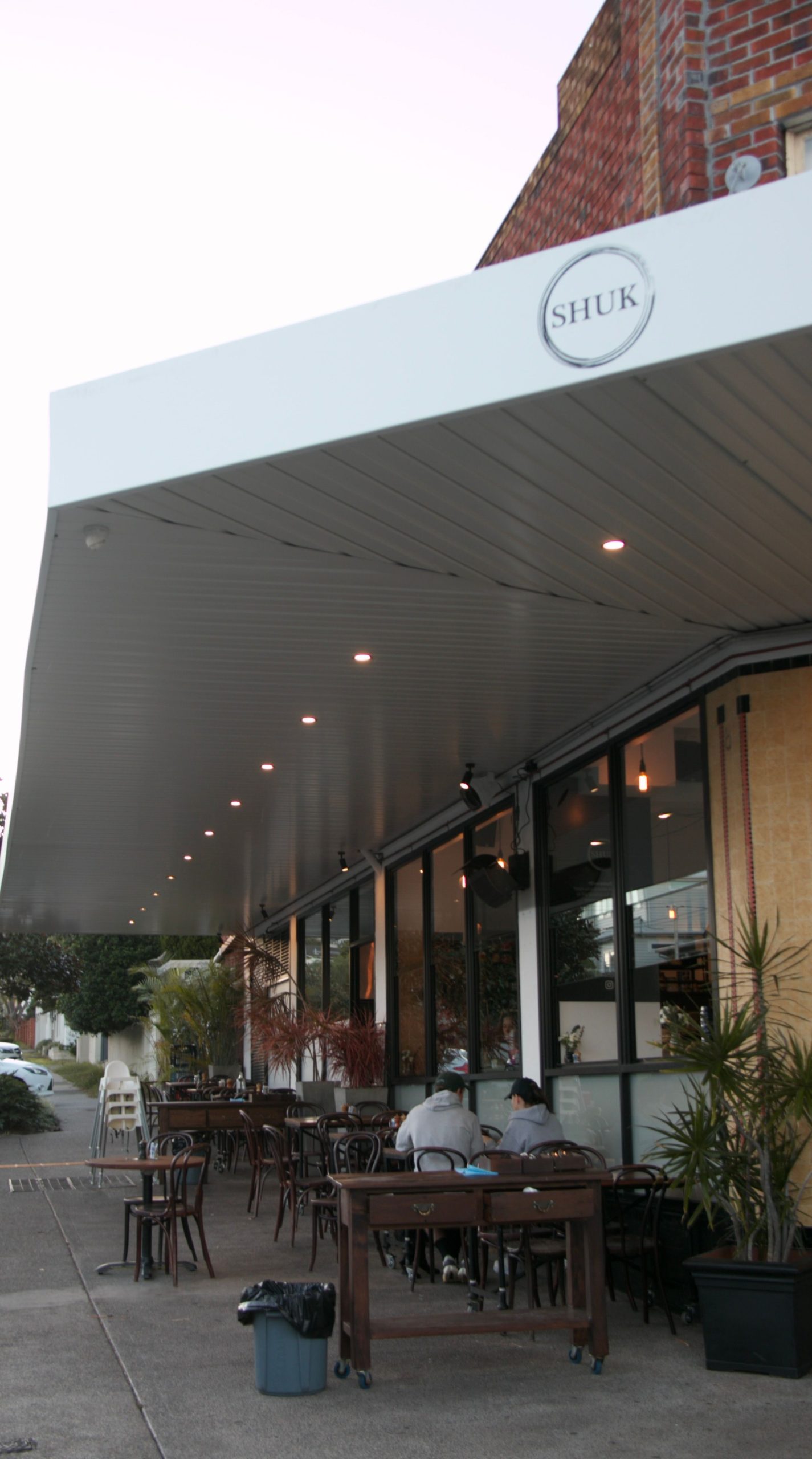 White illuminated awning with recessed downlights over outdoor seating at Shuk restaurant