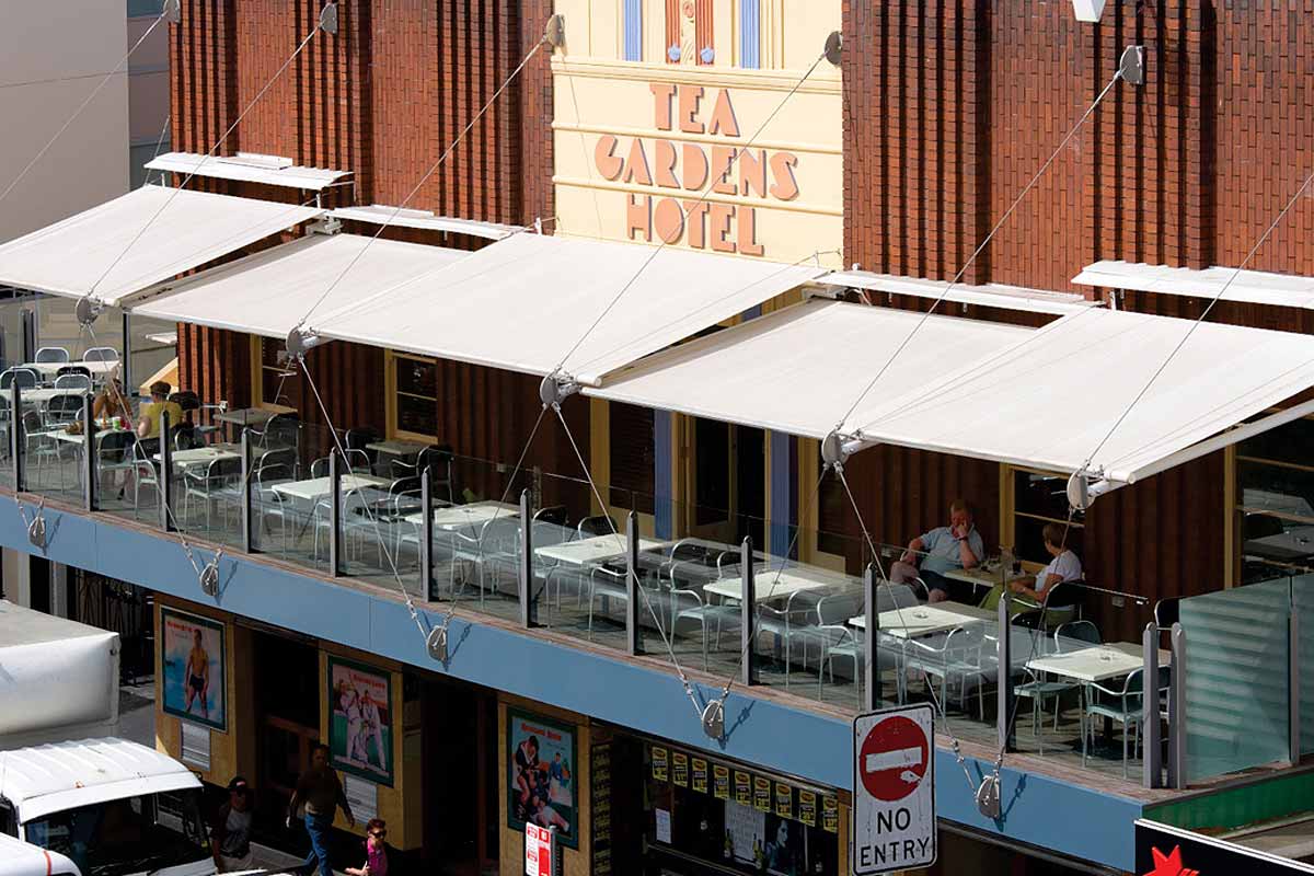 Retractable fabric awnings with tie-rod supports over a rooftop terrace