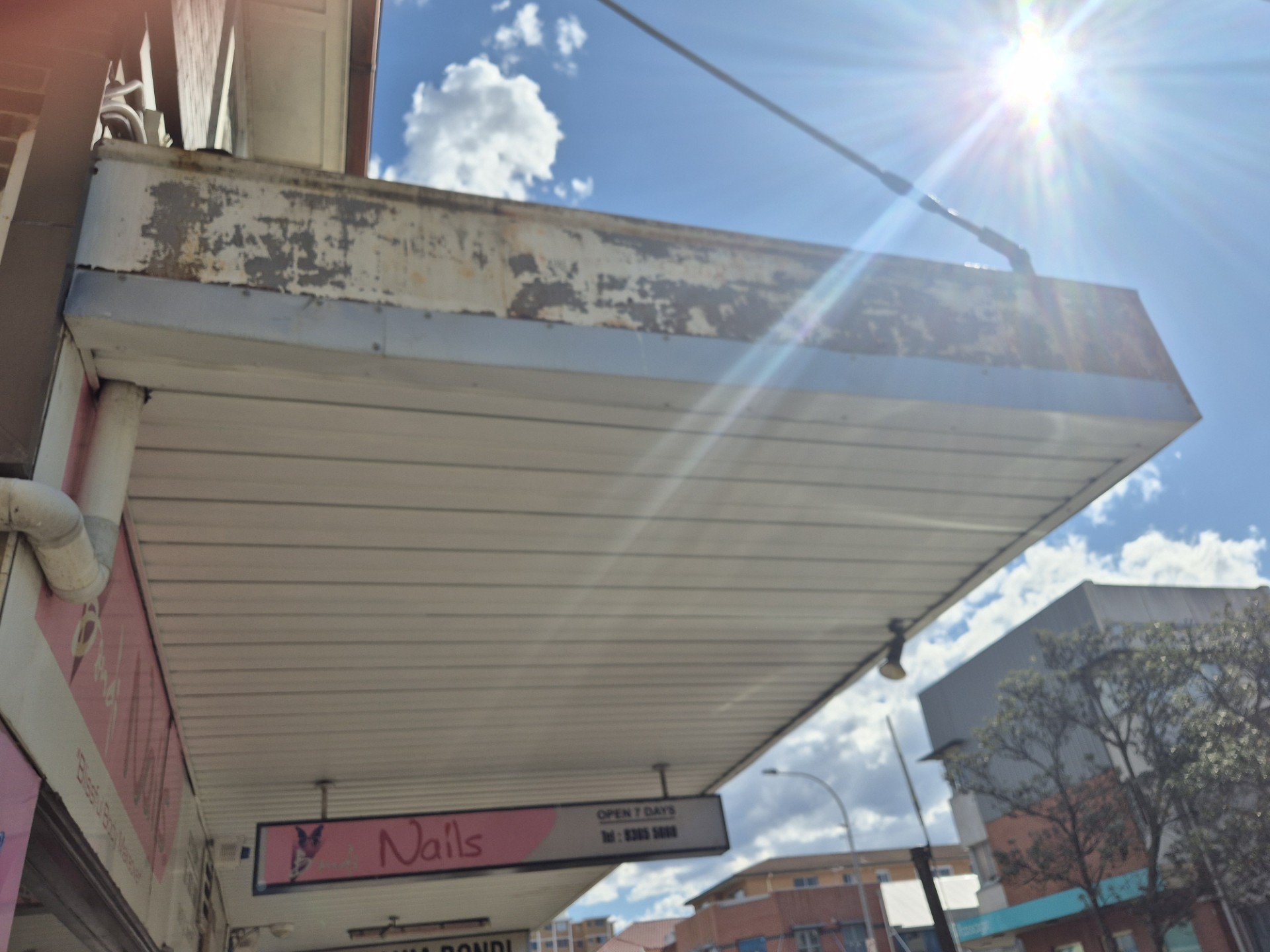 Grimy, rust-streaked underside of a shop awning showing years of built-up dirt and salt residue