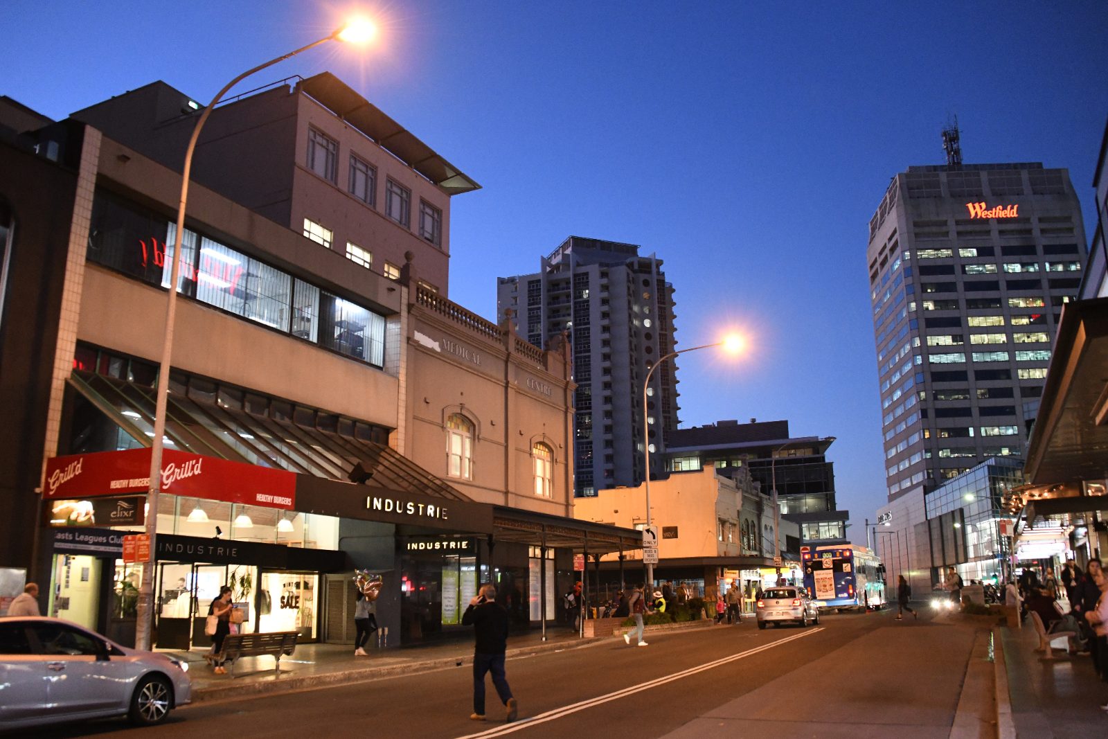 Shopfronts with street awnings along Bronte Road, Bondi Junction at dusk