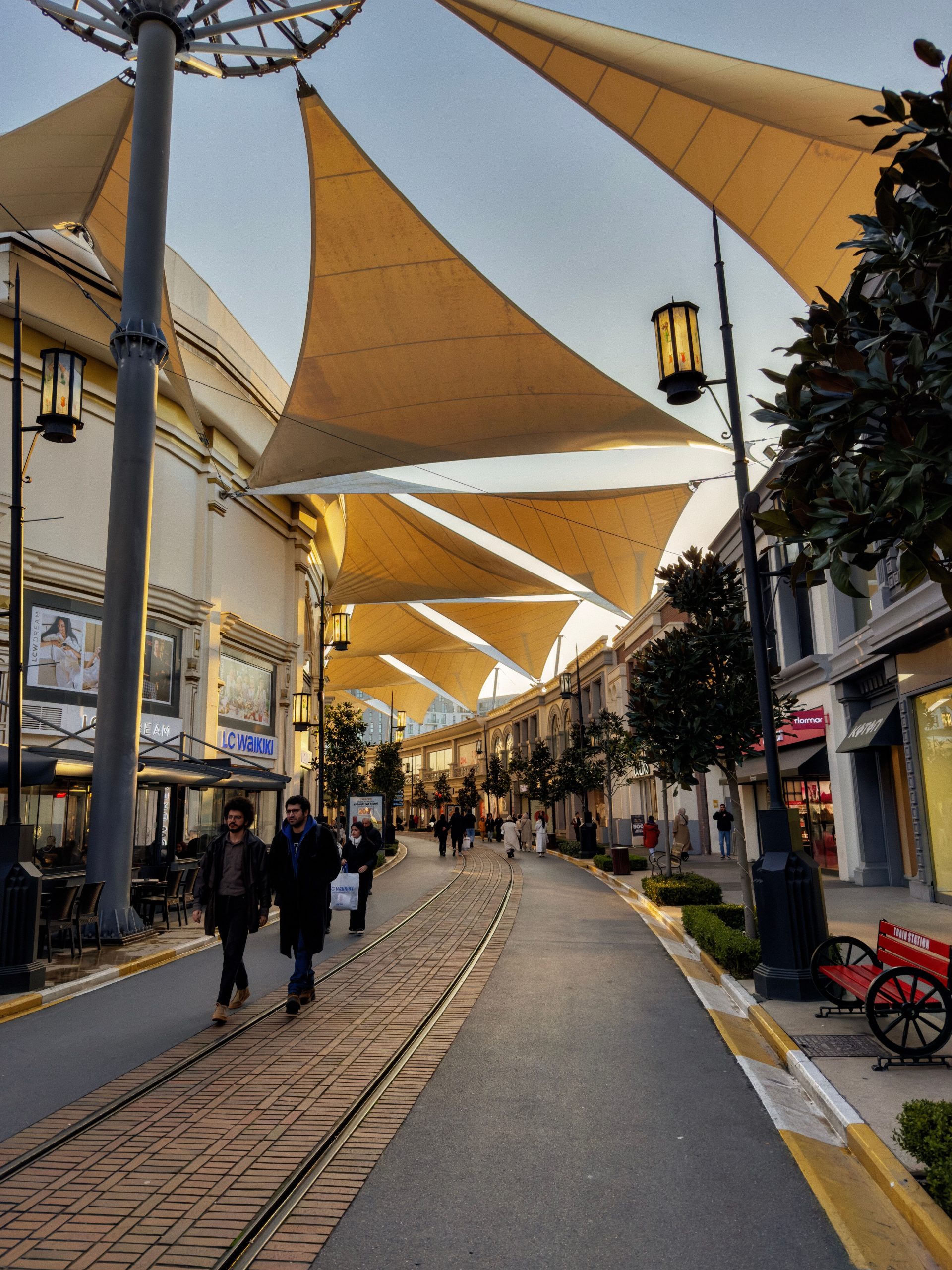 A freestanding fabric canopy supported on its own posts over a pedestrian shopping street