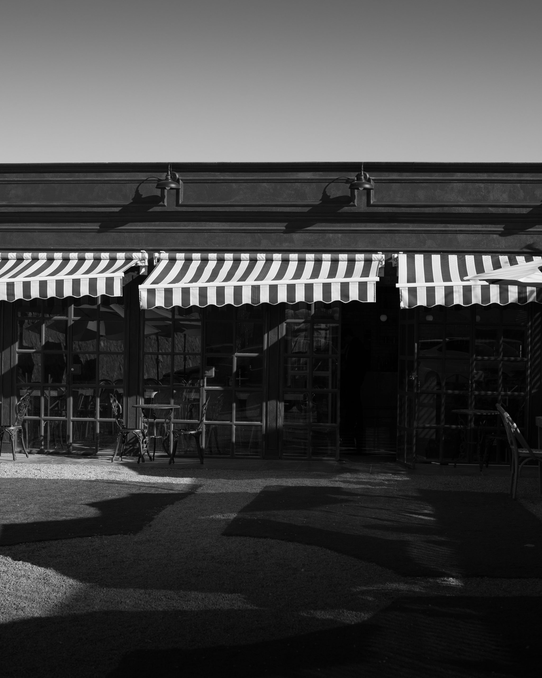 Striped retractable folding-arm awnings mounted directly to a shopfront facade