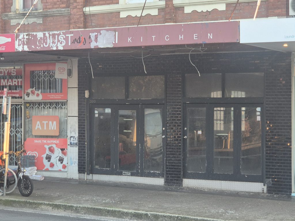 Street awning on Bondi Road with its soffit linings stripped out and old wiring hanging below the frame
